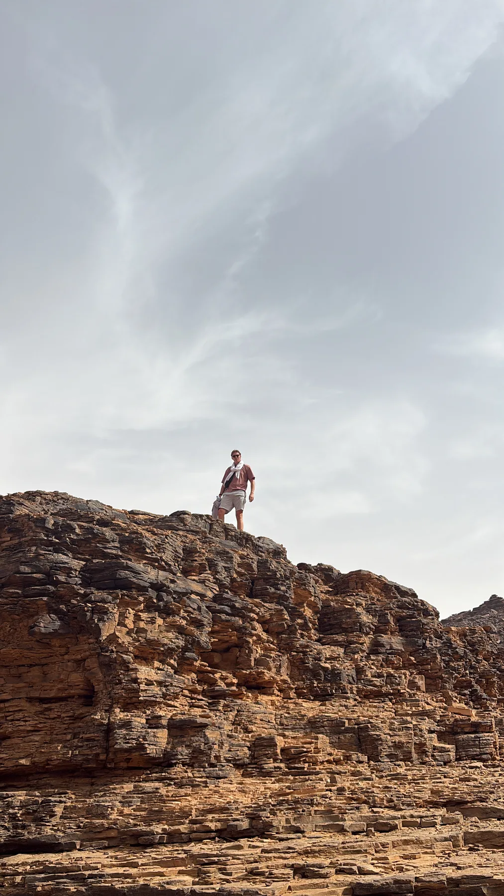 A traveler on a rocky desert ridge in Mauritania — the overland route from Dakhla into the Sahara